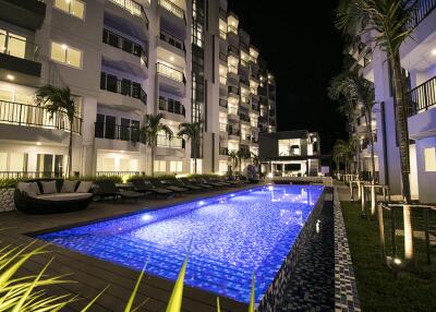 Outdoor pool area at night with apartment buildings