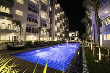 Outdoor pool area at night with apartment buildings