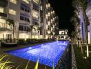 Outdoor pool area at night with apartment buildings