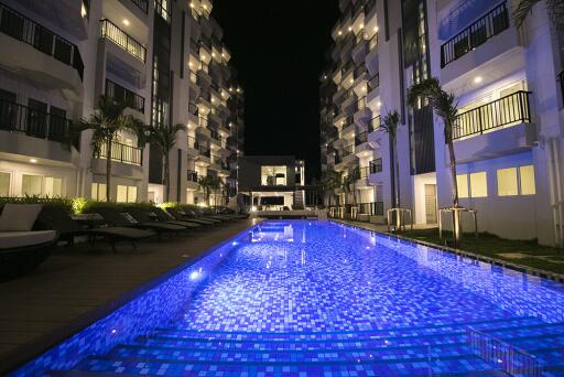 Night view of a well-lit swimming pool surrounded by modern apartment buildings