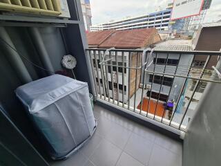 A balcony with building views and a covered appliance