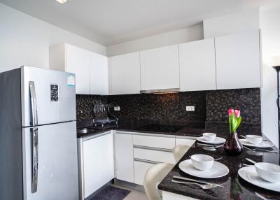 Modern kitchen with sleek white cabinets, black backsplash, and a breakfast bar