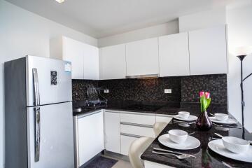 Modern kitchen with sleek white cabinets, black backsplash, and a breakfast bar