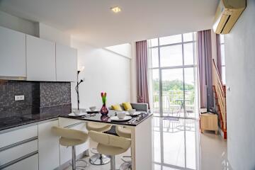 Modern open-plan living room and kitchen with large windows.