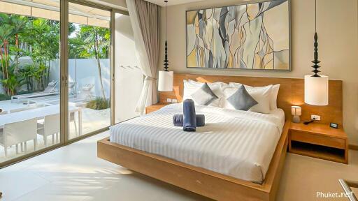 Modern bedroom with large bed, artwork, and view of private outdoor patio