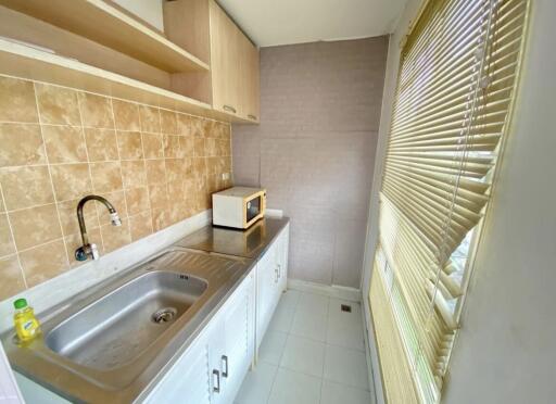 Compact kitchen with tile backsplash, cabinets, blinds, and stainless steel sink