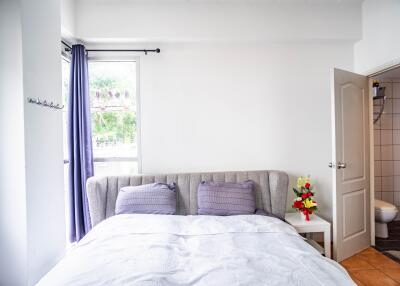 Bright bedroom with double bed, side table, and en-suite bathroom