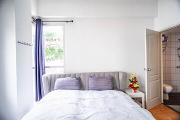 Bright bedroom with double bed, side table, and en-suite bathroom