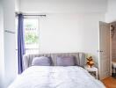 Bright bedroom with double bed, side table, and en-suite bathroom