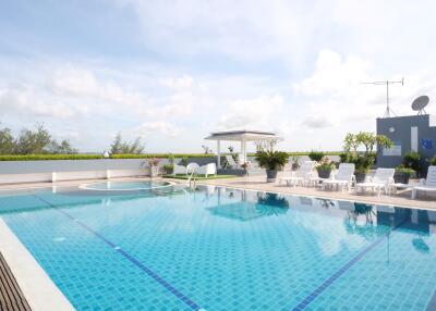 Rooftop swimming pool with lounge chairs and shaded seating