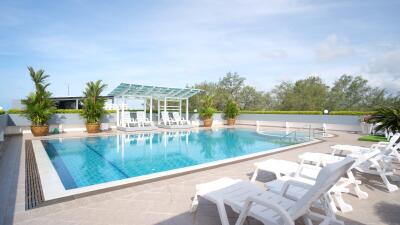 Outdoor swimming pool area with lounge chairs and palm trees