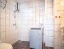 Clean bathroom with washing machine, shower, and toilet