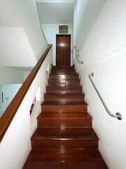 Indoor wooden staircase with handrails and a door at the top