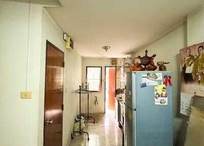 View of a hallway kitchen with a refrigerator and open door