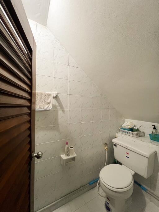 Compact bathroom with toilet and tiled walls