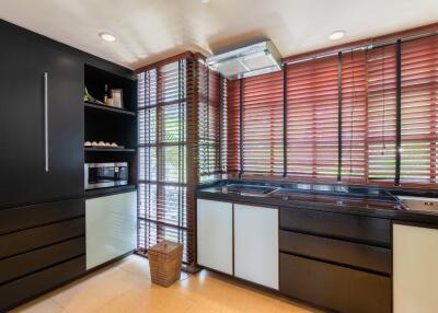 Modern kitchen with dark cabinets and large windows with blinds