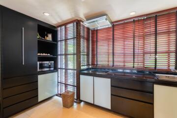 Modern kitchen with dark cabinets and large windows with blinds