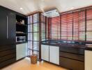 Modern kitchen with dark cabinets and large windows with blinds