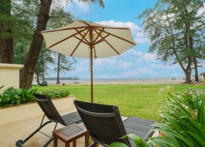 Beach view from patio with lounge chairs and umbrella