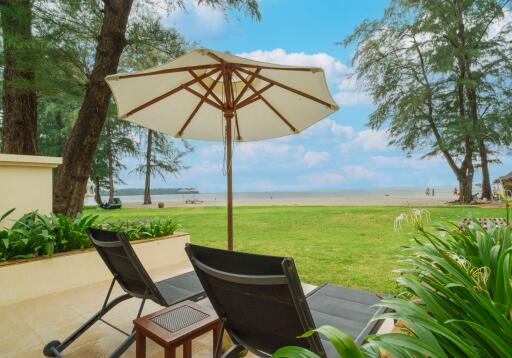 Beach view from patio with lounge chairs and umbrella