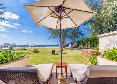 Seaside view from a relaxing outdoor lounge area with chairs and umbrella