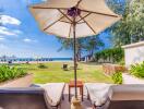 Seaside view from a relaxing outdoor lounge area with chairs and umbrella