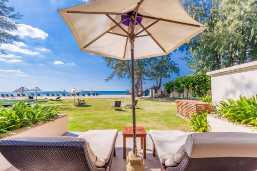 Seaside view from a relaxing outdoor lounge area with chairs and umbrella