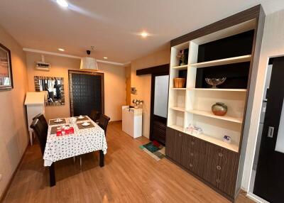 Dining area with table and chairs, wooden floor, and built-in shelving