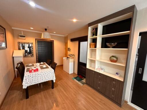 Dining area with table and chairs, wooden floor, and built-in shelving