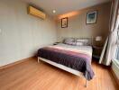 Modern bedroom with wooden flooring, a double bed, and wall-mounted air conditioning.