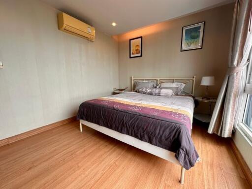 Modern bedroom with wooden flooring, a double bed, and wall-mounted air conditioning.