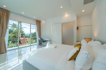 Bright and airy bedroom with large windows, desk, and cozy bedding