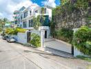 Modern white building exterior with lush greenery and stone wall