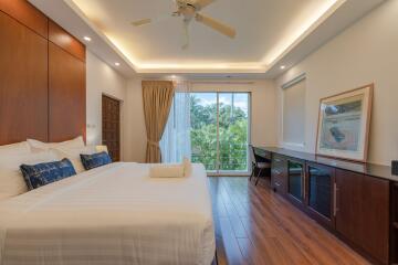 Spacious bedroom with wooden flooring, large bed, and a balcony view