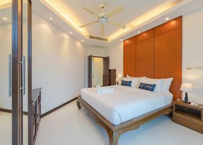 Modern bedroom with wooden accents, large bed, ceiling fan, and ambient lighting