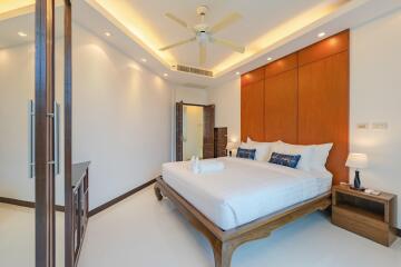 Modern bedroom with wooden accents, large bed, ceiling fan, and ambient lighting