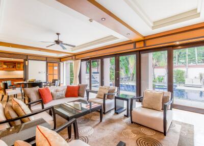 Spacious and well-lit living room with a view of the pool and greenery