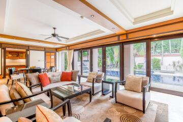 Spacious and well-lit living room with a view of the pool and greenery