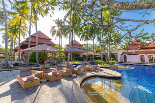 Luxurious outdoor pool area with sun lounges and tropical surroundings