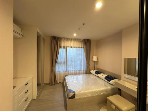 Modern bedroom with double bed, window with curtains, vanity area, and air conditioning unit