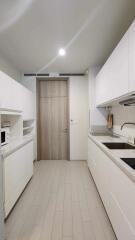 Modern kitchen with white cabinetry and wooden door