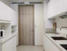 Modern kitchen with white cabinetry and wooden door