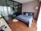 Cozy bedroom with wooden flooring, a large bed, and a glass partition.