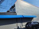 Exterior view of a building with a blue awning and a parked car