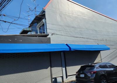 Exterior view of a building with blue awnings and parked car
