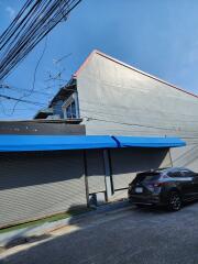 Exterior view of a building with blue awnings and parked car