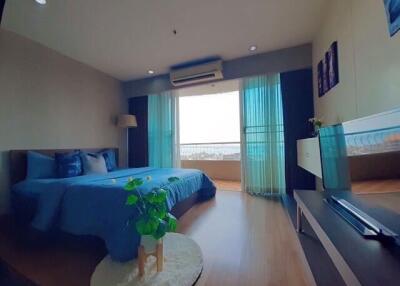 A modern bedroom with a large bed, air conditioning, and a large window with blue curtains.