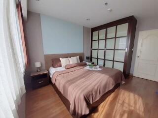 A well-lit bedroom with a large bed, nightstand, lamp, and built-in closet