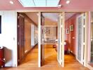 Interior view with folding wooden doors, wooden flooring, and artworks on the walls