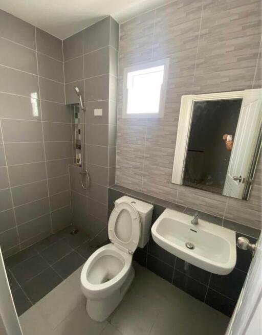 Modern bathroom with a toilet, sink, shower, and small window.